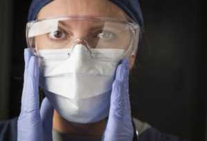 Nurse protecting herself from patient in isolation.