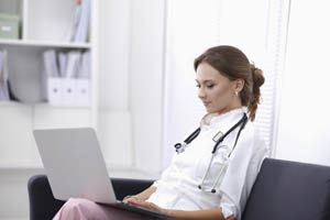 female nurse sitting chair using latop