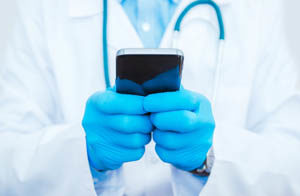 doctor with stethoscope holding a smartphone