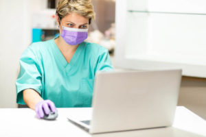 healthcare-worker-working-on-laptop-with-mask-and-gloves