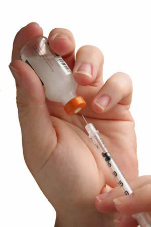 hand syringe pulling medicine from vial