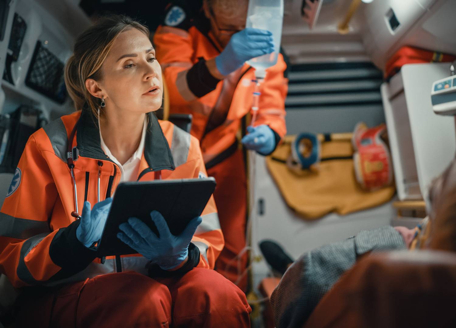 Paramedic assessing a patient in an ambulance.