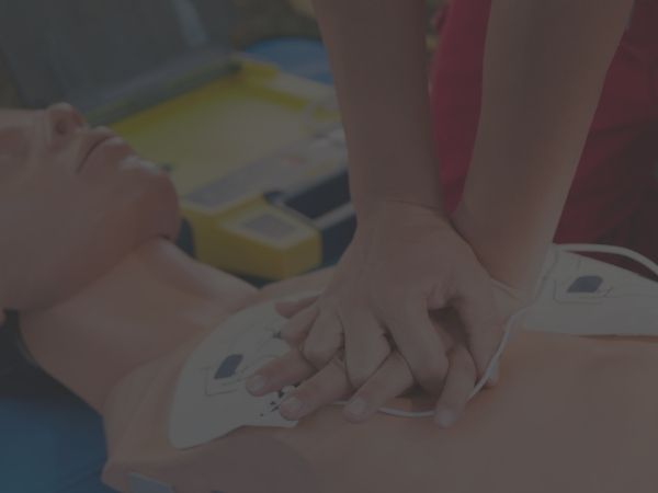 Close-up of hands performing CPR on a mannequin to improve chest compression fraction during cardiac arrest training.