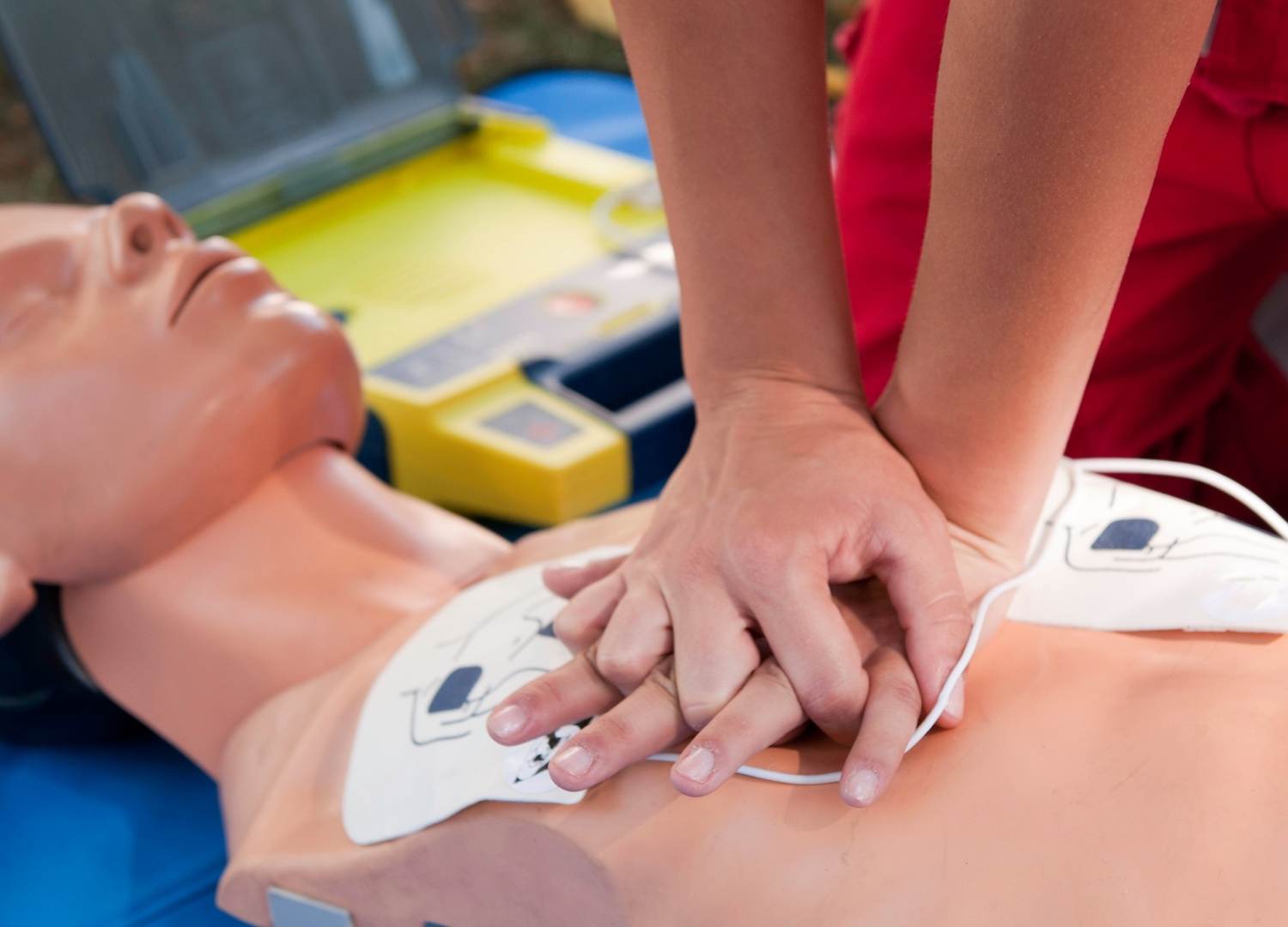 Close-up of hands performing CPR on a mannequin to improve chest compression fraction during cardiac arrest training.