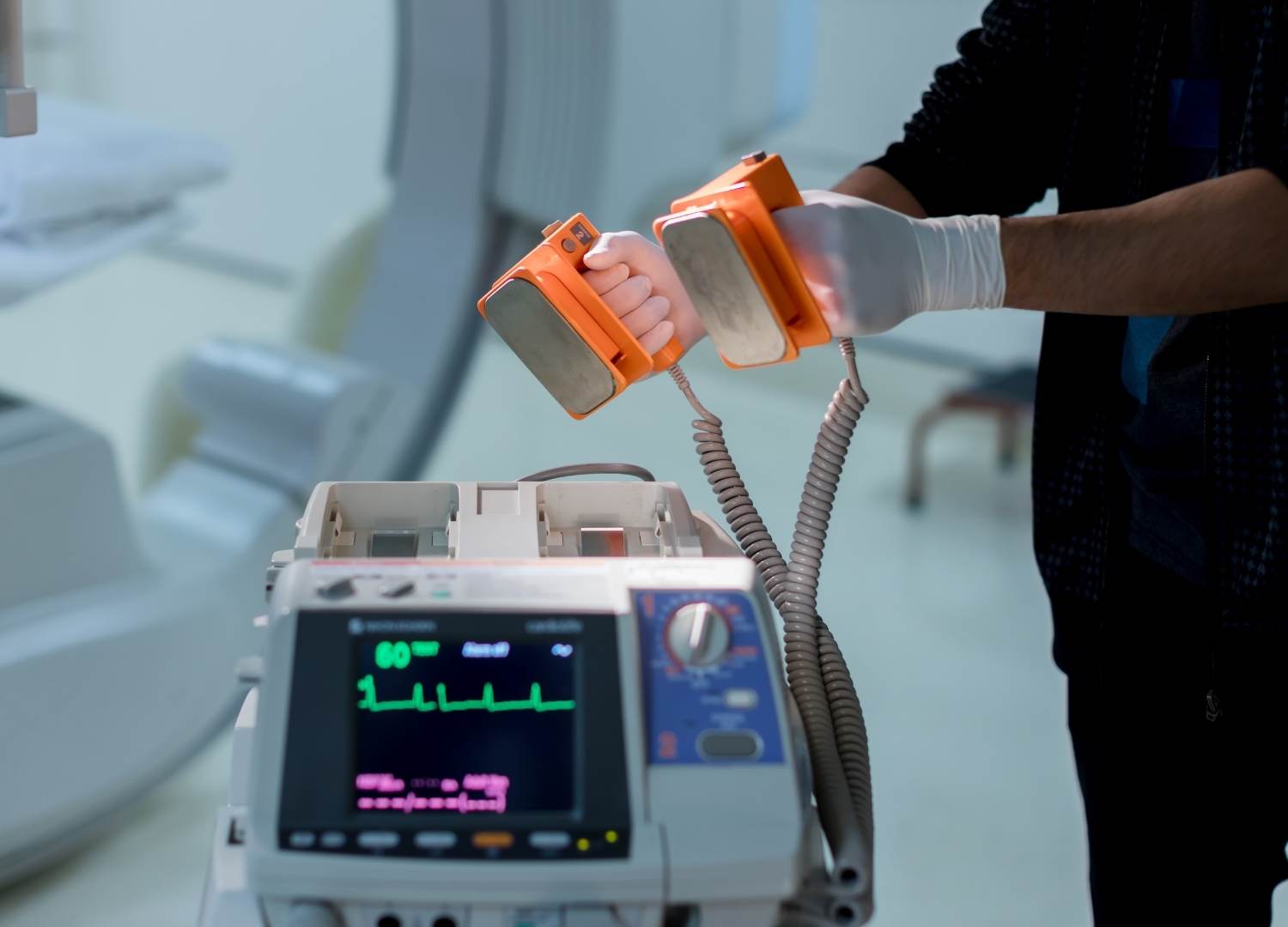 Healthcare professional using a defibrillator to administer a shock during cardiac arrest.