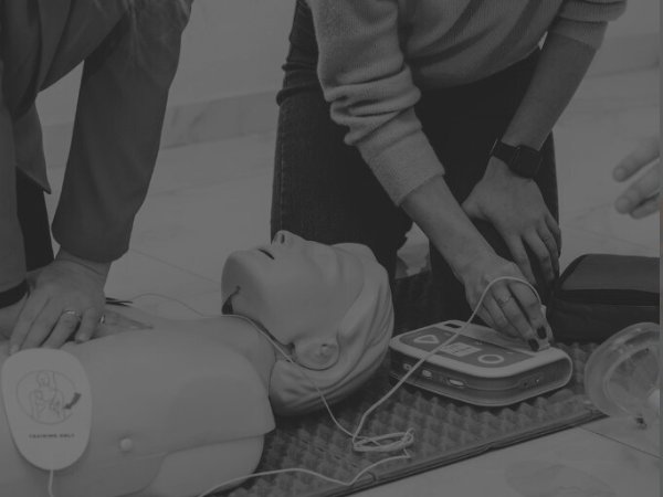 group of people discussing BLS with the use of manikin and aed featured