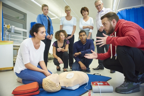 group of people discussing BLS with the use of manikin and aed