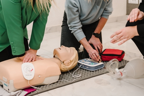 group of people performing compressions with the use of manikin and aed