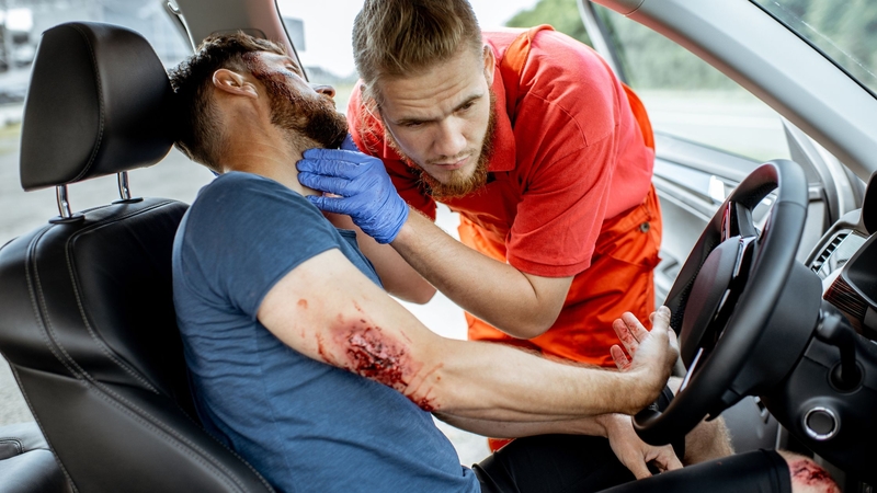 A rescuer examining a car accident patient to determine if he needs the jaw thrust maneuver