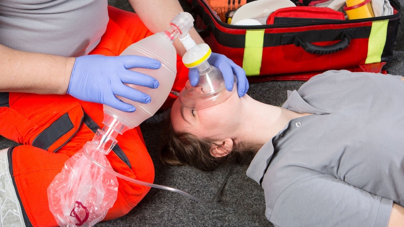 A rescuer applying the bag valve mask ventilation to a patient