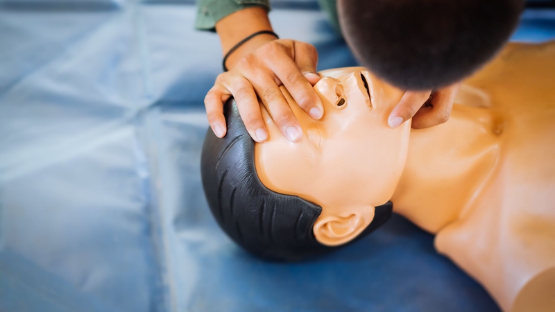 A person doing jaw thrust maneuver with a mannequin