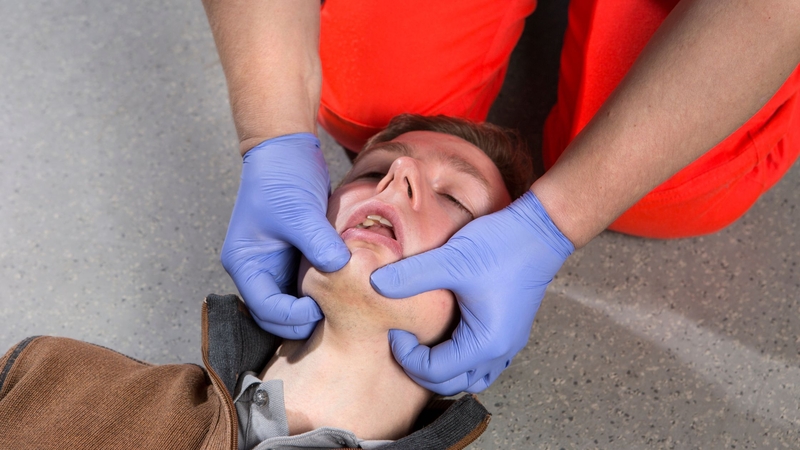 A rescuer performing jaw thrust maneuver to a patient