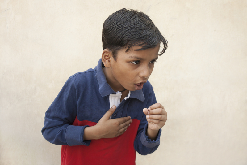 a boy holding his chest while coughing