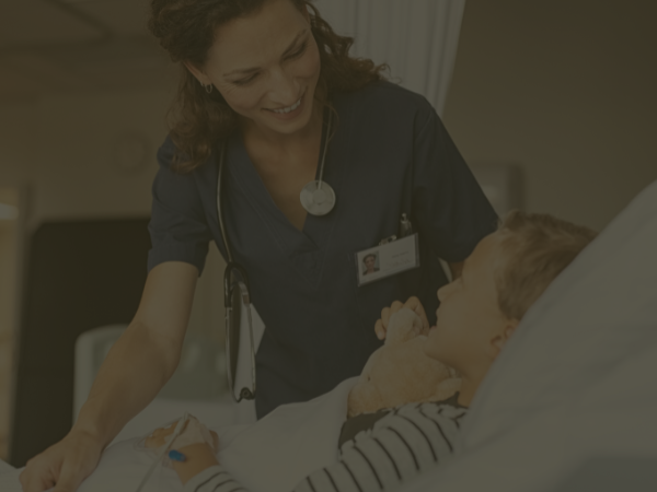 a female nurse assisting a boy patient lying in bed f